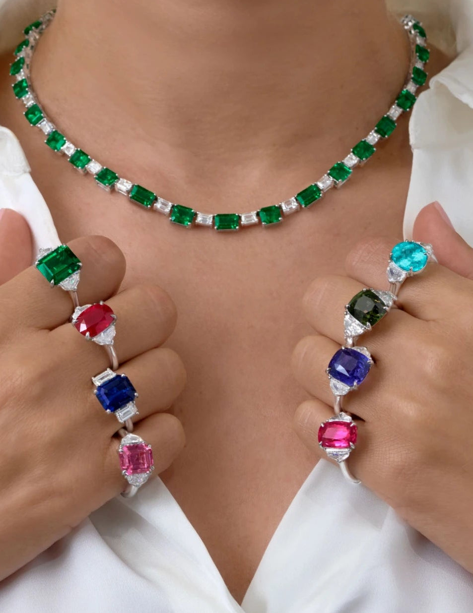 Model wearing an emerald and diamond necklace with emerald, ruby, sapphire and tourmaline gemstone rings