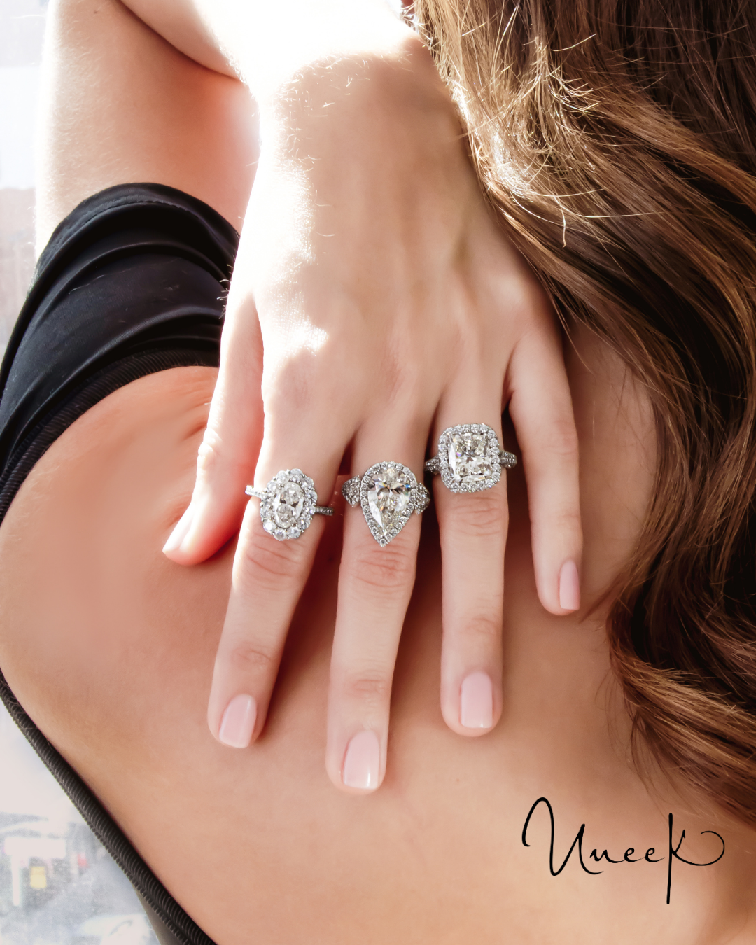 Uneek diamond halo engagement rings on a hand